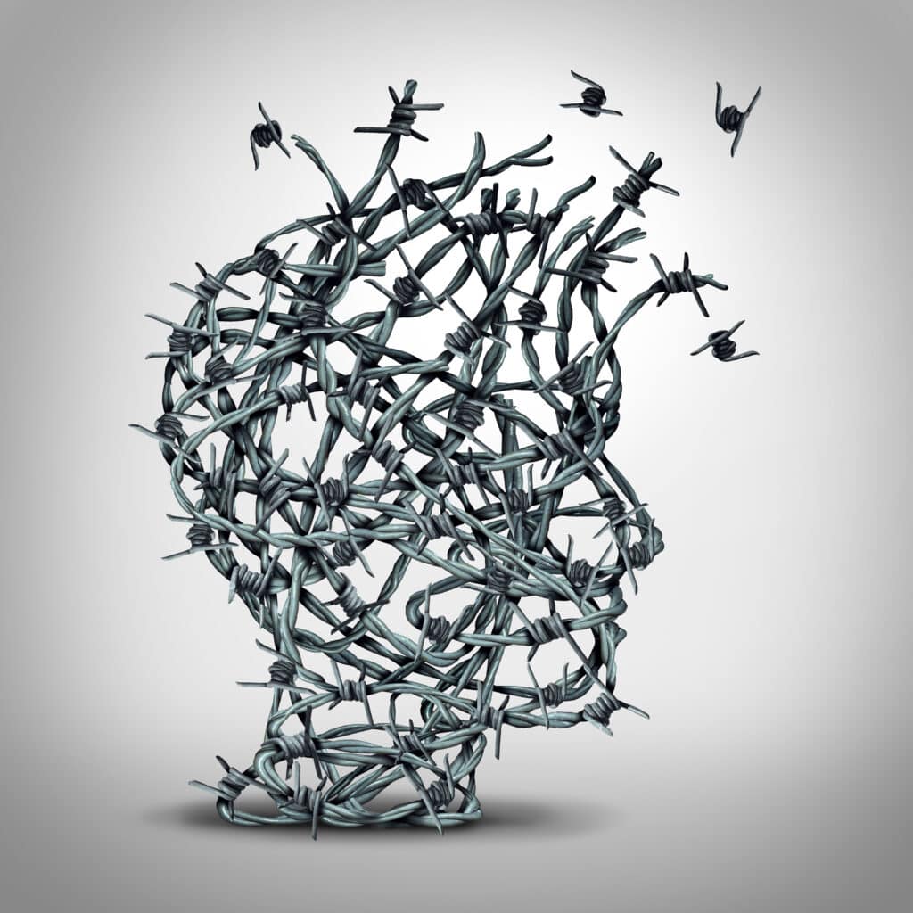 Anxiety solution and freedom from fear and escape from tortured thinking and depression concept as a group of tangled barbwire or barbed wire fence shaped as a human head breaking free as a metaphor for psychological or psychiatric icon.