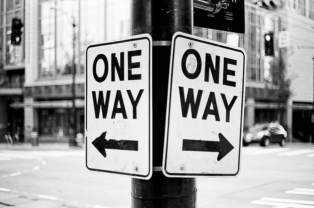 One-way street sign mounted on a pole in a city street.